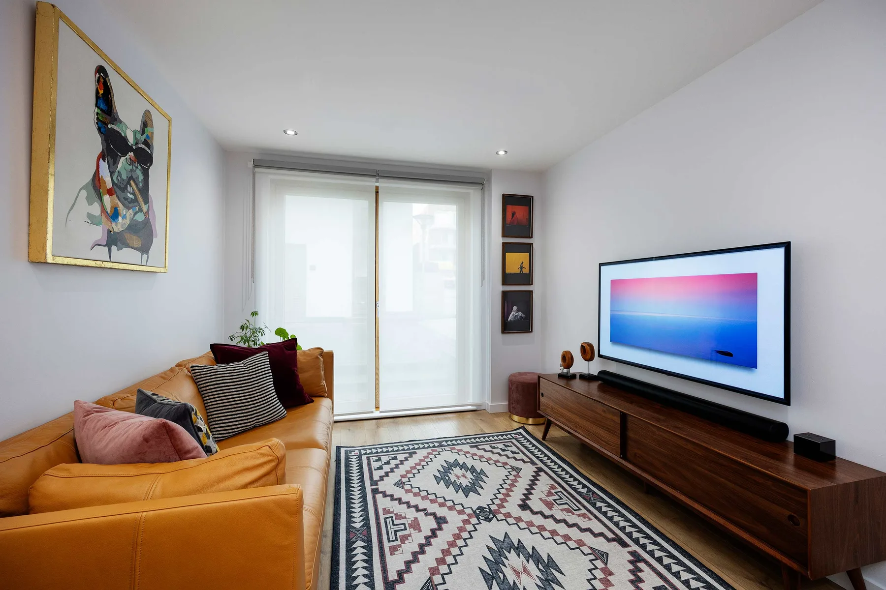 A living room with seating, a patterned rug, and a television.