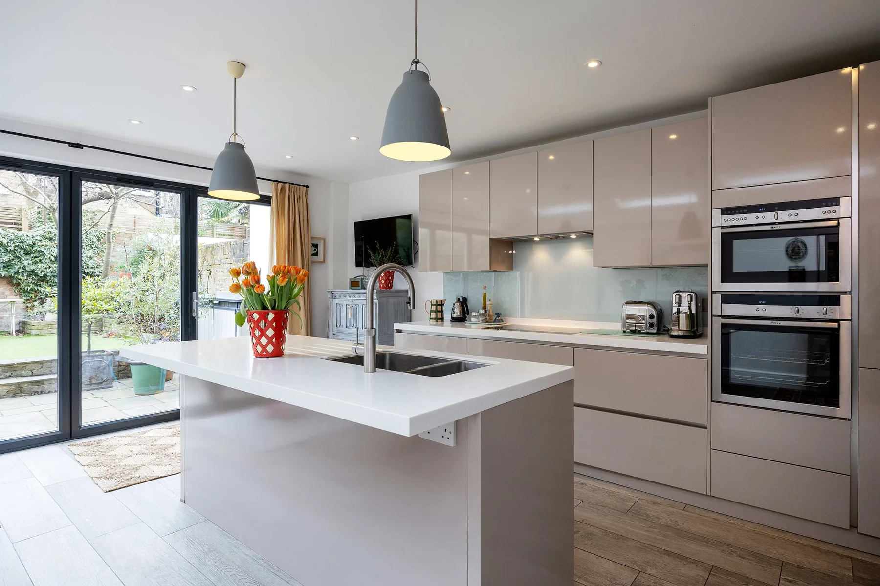 Una cocina moderna y luminosa con una isla blanca y grandes ventanas con vistas al jardín.