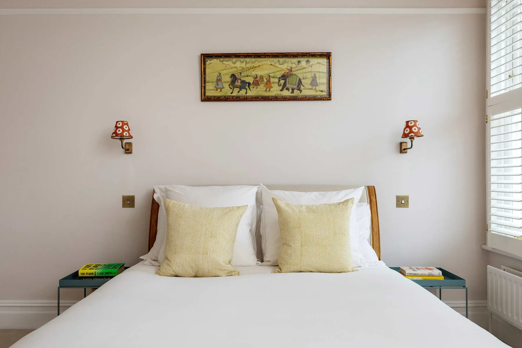 Un dormitorio con una cama bien hecha y un cuadro enmarcado encima.