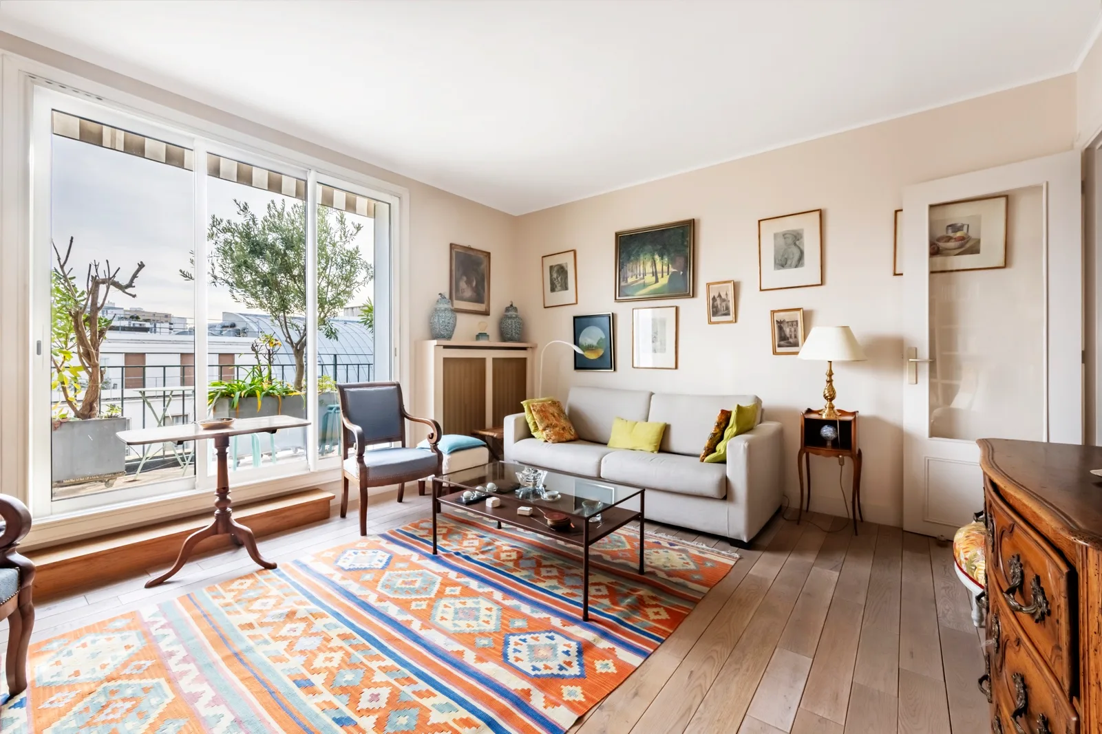 A bright living room with seating, a patterned rug, and large windows.