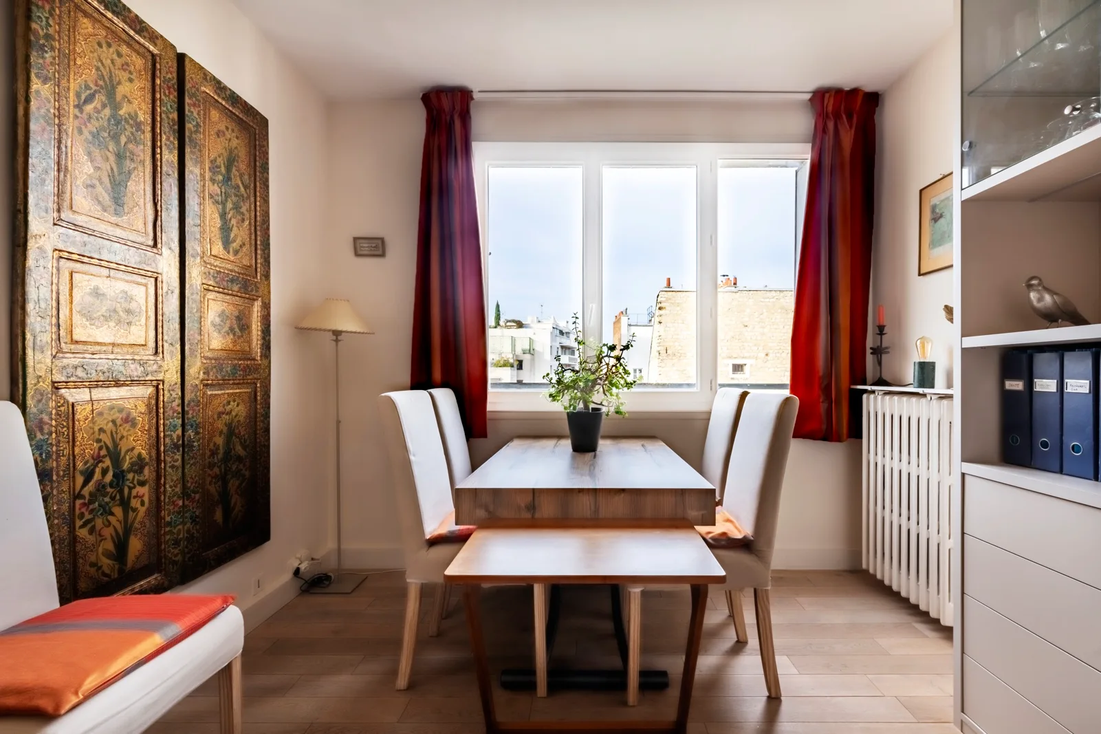 A dining area with a table and chairs beside a bright window.