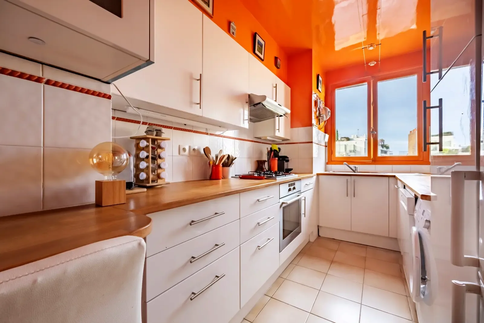 A bright kitchen with white cabinets and a long wooden countertop.