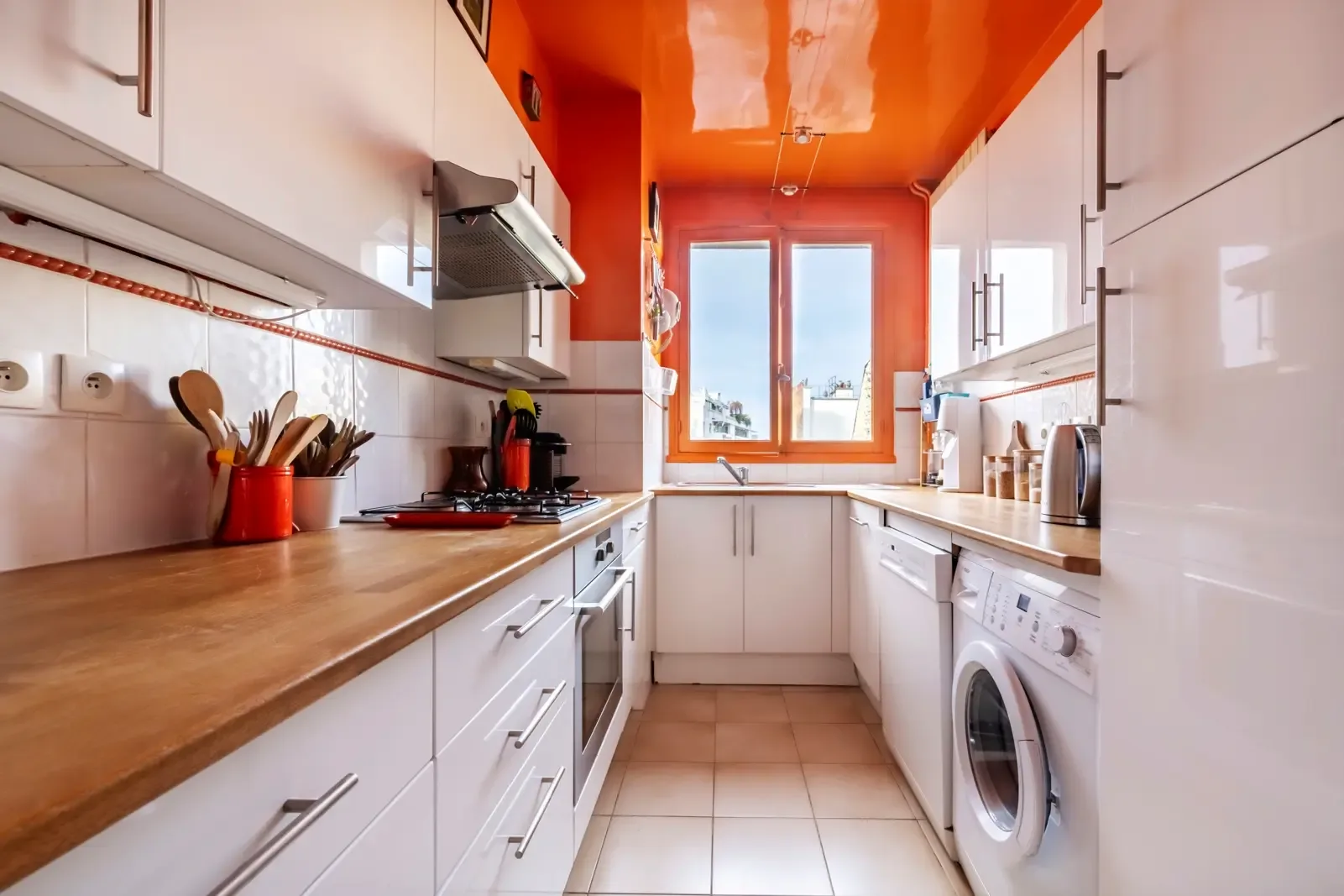 A bright kitchen with white cabinets, wooden counters, and a window.