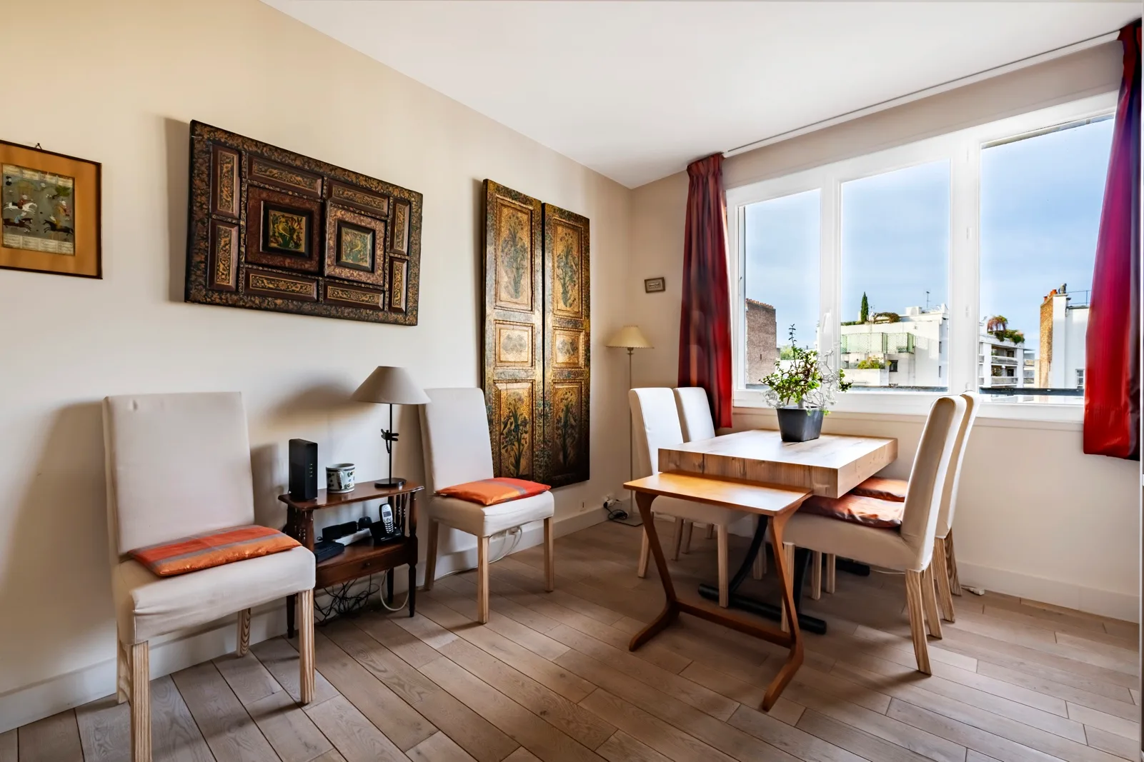 A dining area with a wooden table and chairs beside a large window.
