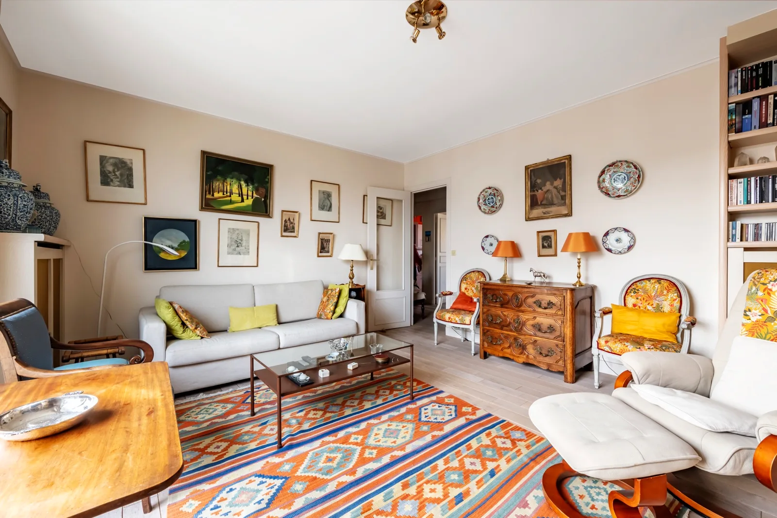 Una sala de estar con asientos alrededor de una mesa de centro y alfombras coloridas.