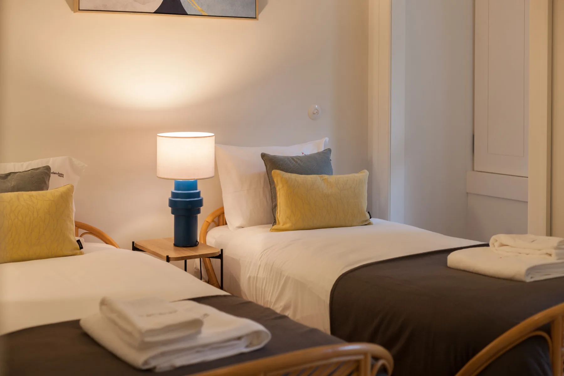 Un dormitorio con dos camas, ropa de cama blanca y lámparas de noche.