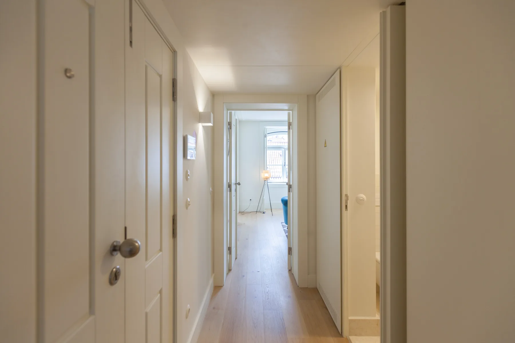 Un pasillo luminoso conduce a una habitación con ventana.