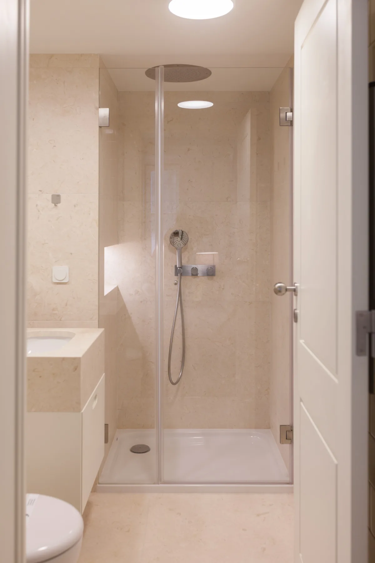 Un baño con azulejos, ducha de cristal y un inodoro parcialmente visible.
