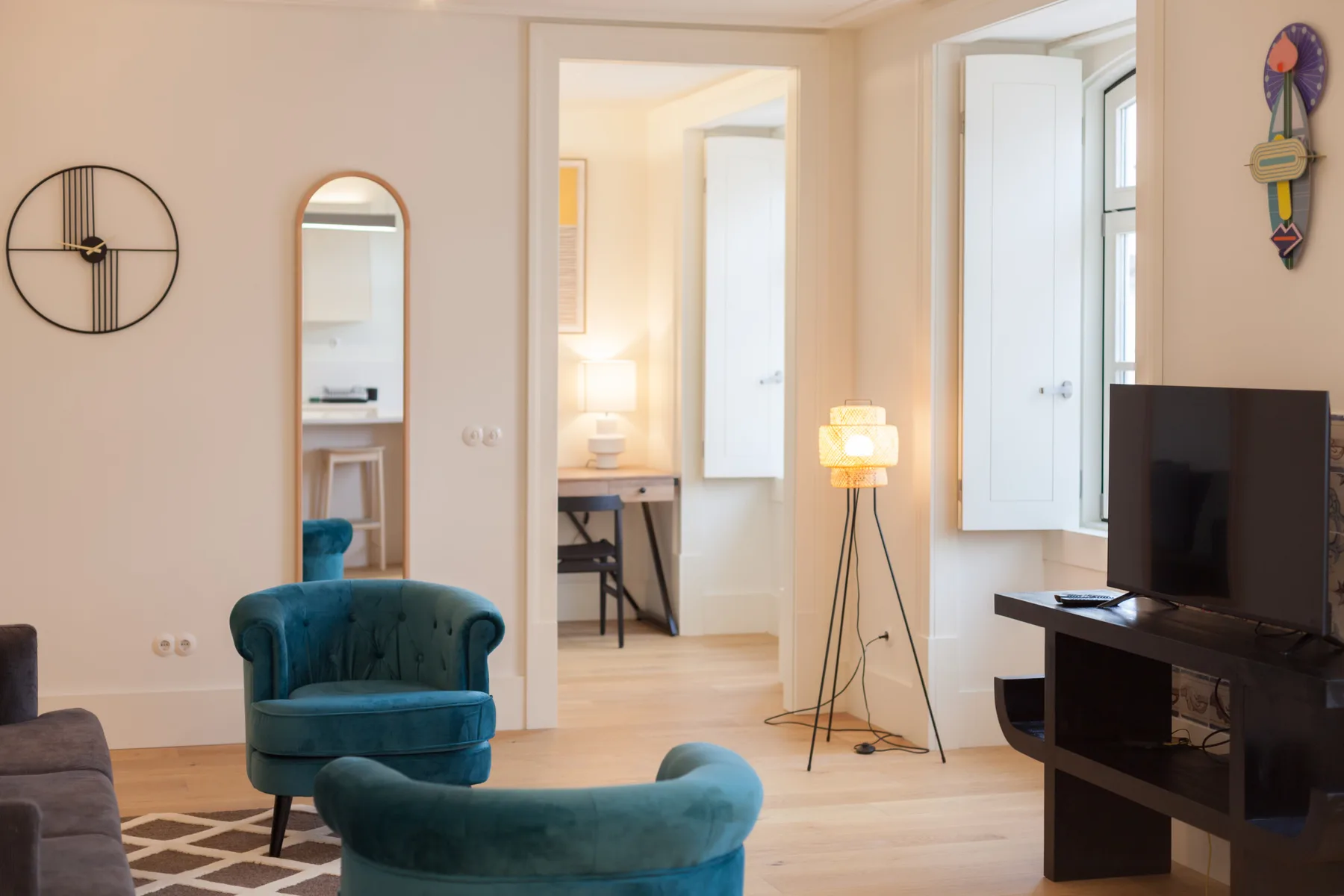 Una sala luminosa con asientos color turquesa, un televisor y una puerta abierta.