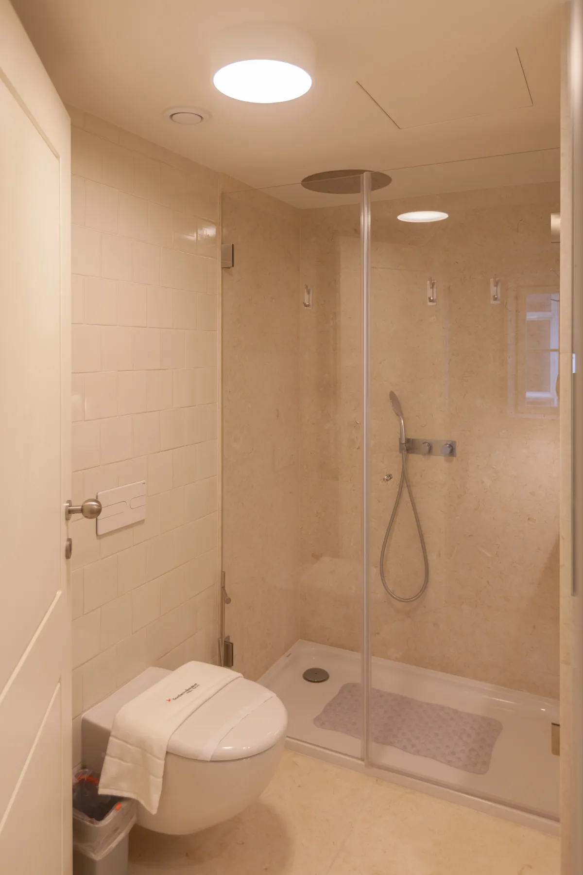 Un baño alicatado con ducha a ras de suelo e inodoro suspendido.
