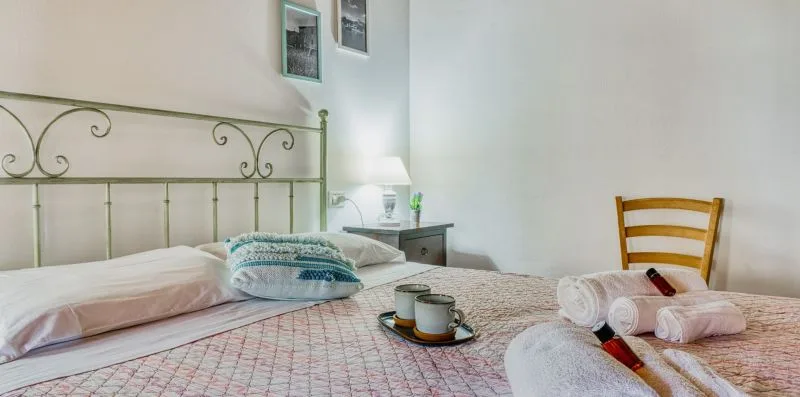 A bedroom with a bed, bedside table, and wooden chair.