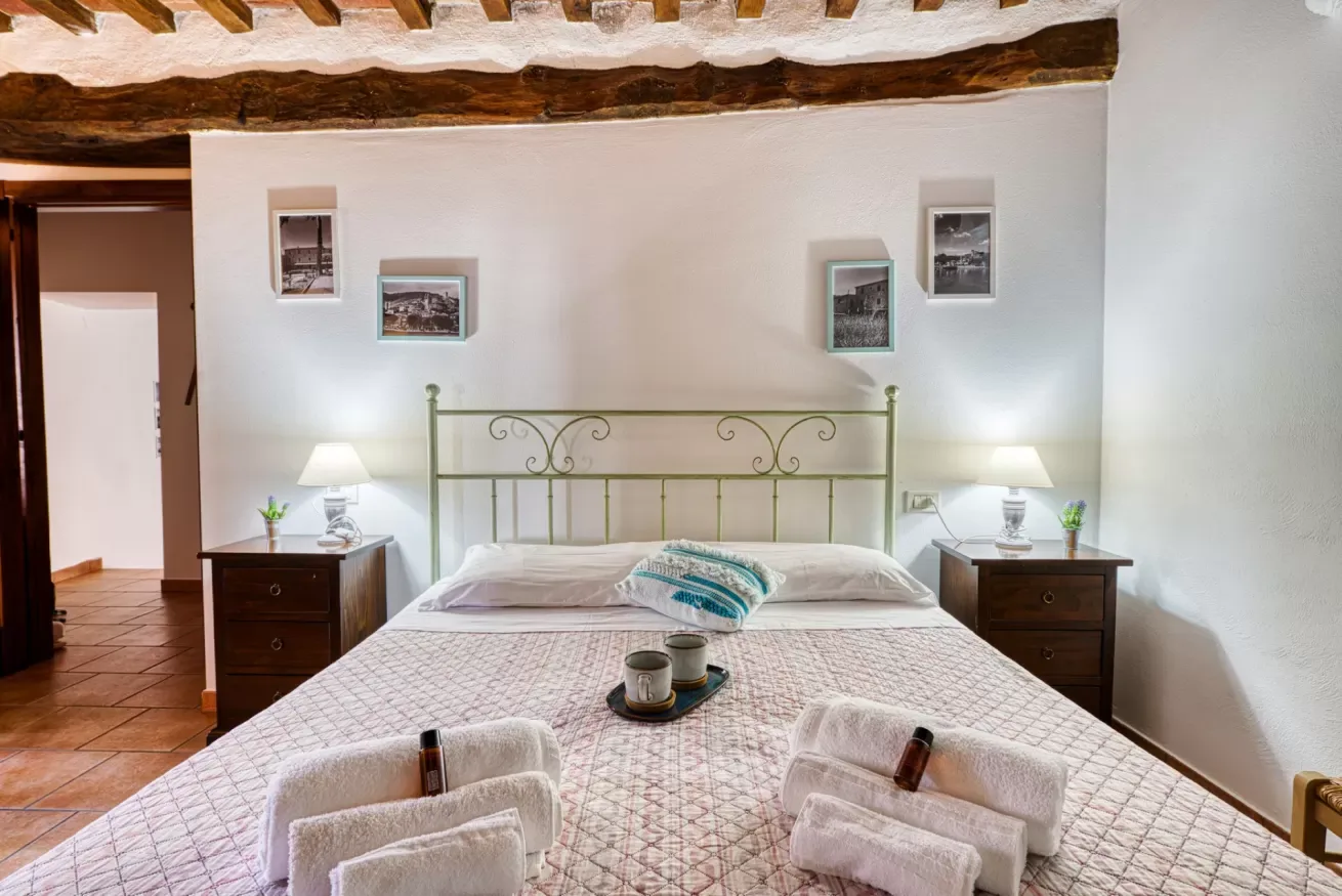 A bedroom with a large bed, bedside tables, and framed pictures on the wall.