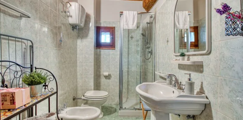 A tiled bathroom with a glass shower, toilet, and sink.