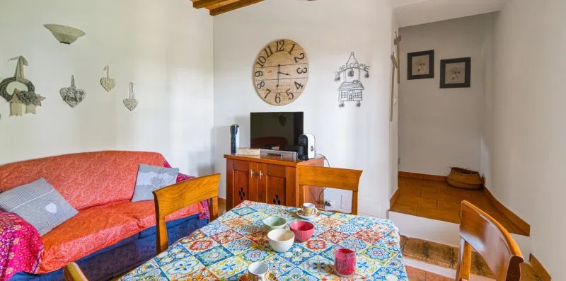 A living room has a patterned tablecloth-covered table and red seating.