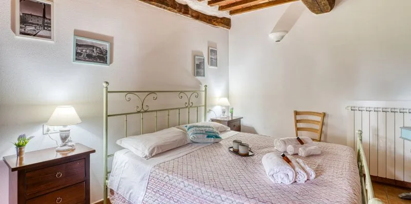 A bedroom with a double bed, bedside table, and exposed ceiling beams.