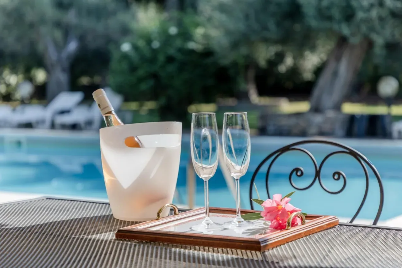 A drink tray with glasses sits beside a swimming pool.