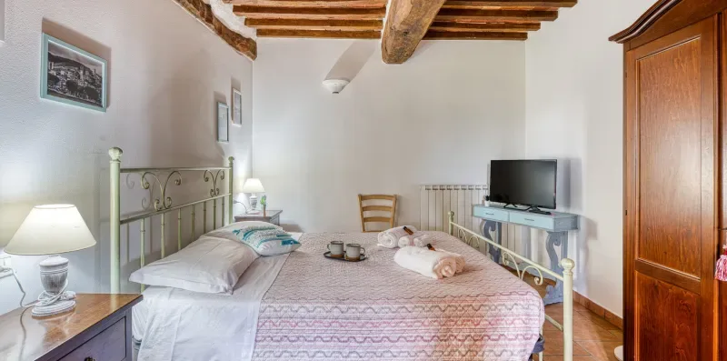 A bedroom with a bed, bedside tables, and a television.
