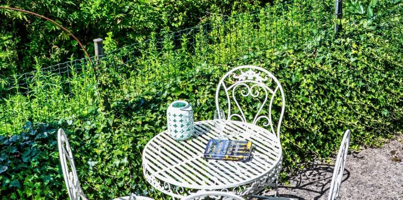 A small garden seating area with a round table and white metal chairs.