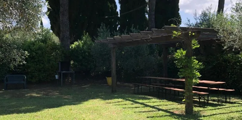 A garden seating area with a wooden pergola and picnic tables.