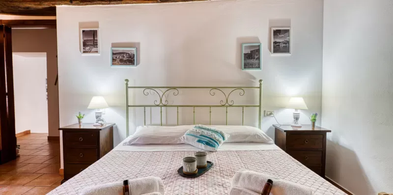A bedroom with a double bed, bedside tables, and framed pictures on the wall.