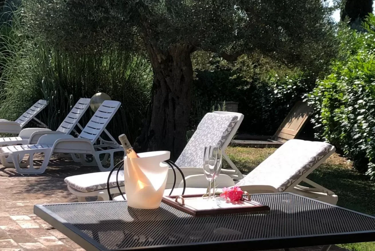 A shaded outdoor patio has lounge seating arranged around a table.