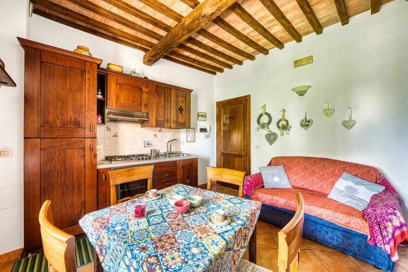 A dining and living area has wooden cabinetry, a patterned tablecloth, and a sofa.