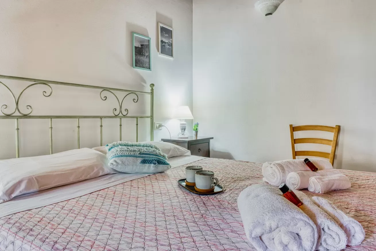 A bedroom with a neatly made bed and folded towels.