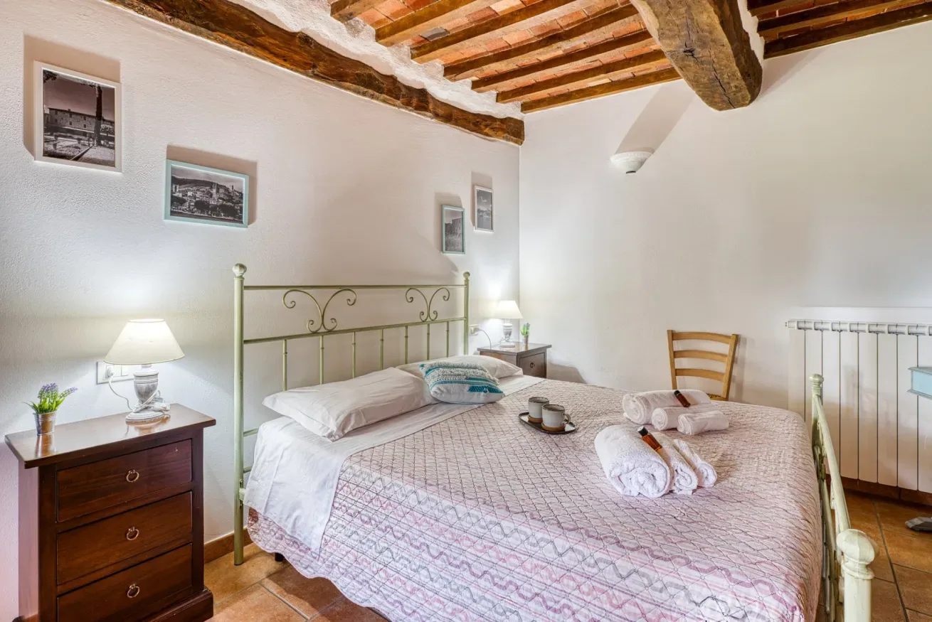 A bedroom with a metal bed, bedside tables, and exposed wooden ceiling beams.