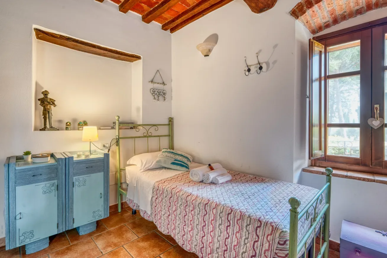 A bedroom with a single bed, green metal headboard, and blue cabinet.