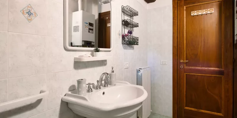 A tiled bathroom with a sink and a wooden door.