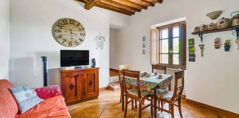 A dining and living area with a table, chairs, and a television.