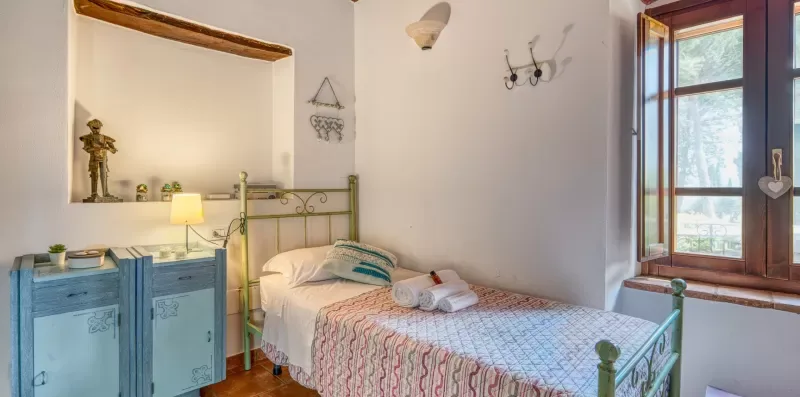 A bedroom with a metal bed, folded towels, and a blue cabinet.
