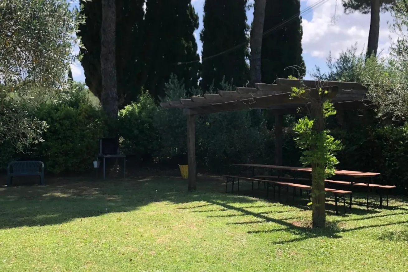 A grassy garden with a wooden pergola and outdoor seating.