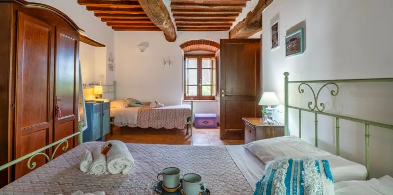 A bedroom with a bed, wooden ceiling beams, and a window.