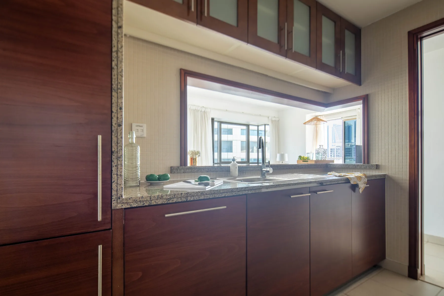 Una encimera de cocina con gabinetes de madera oscura y una amplia abertura hacia una ventana.