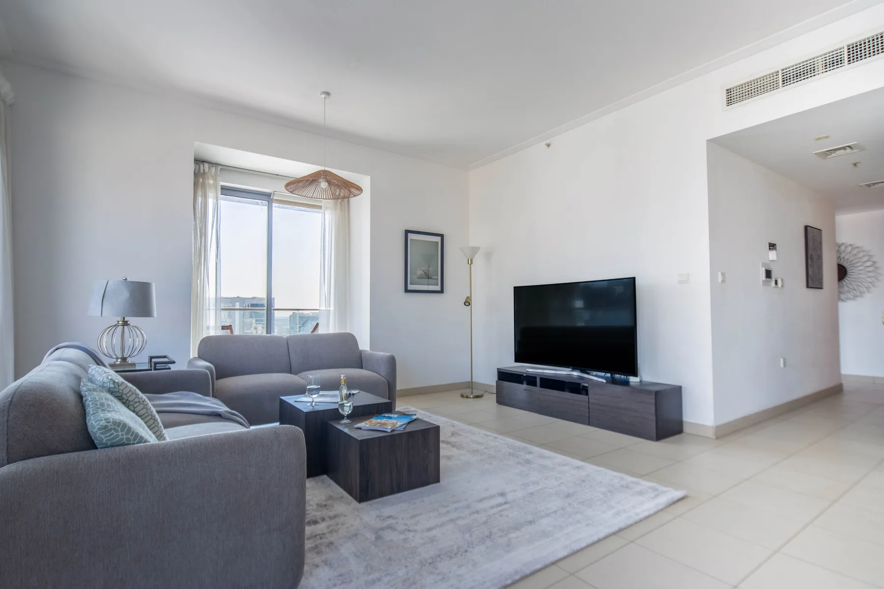 Una sala luminosa con asientos, un televisor y una ventana grande.