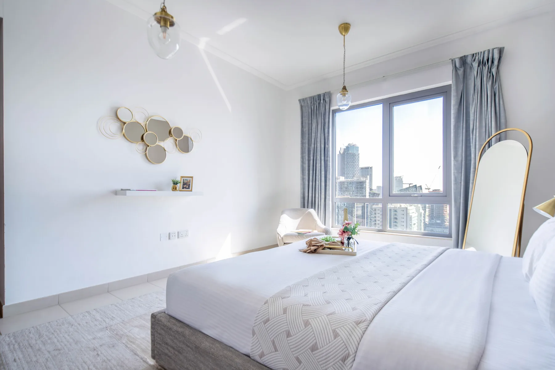 Un dormitorio luminoso con una cama bien hecha junto a una gran ventana.