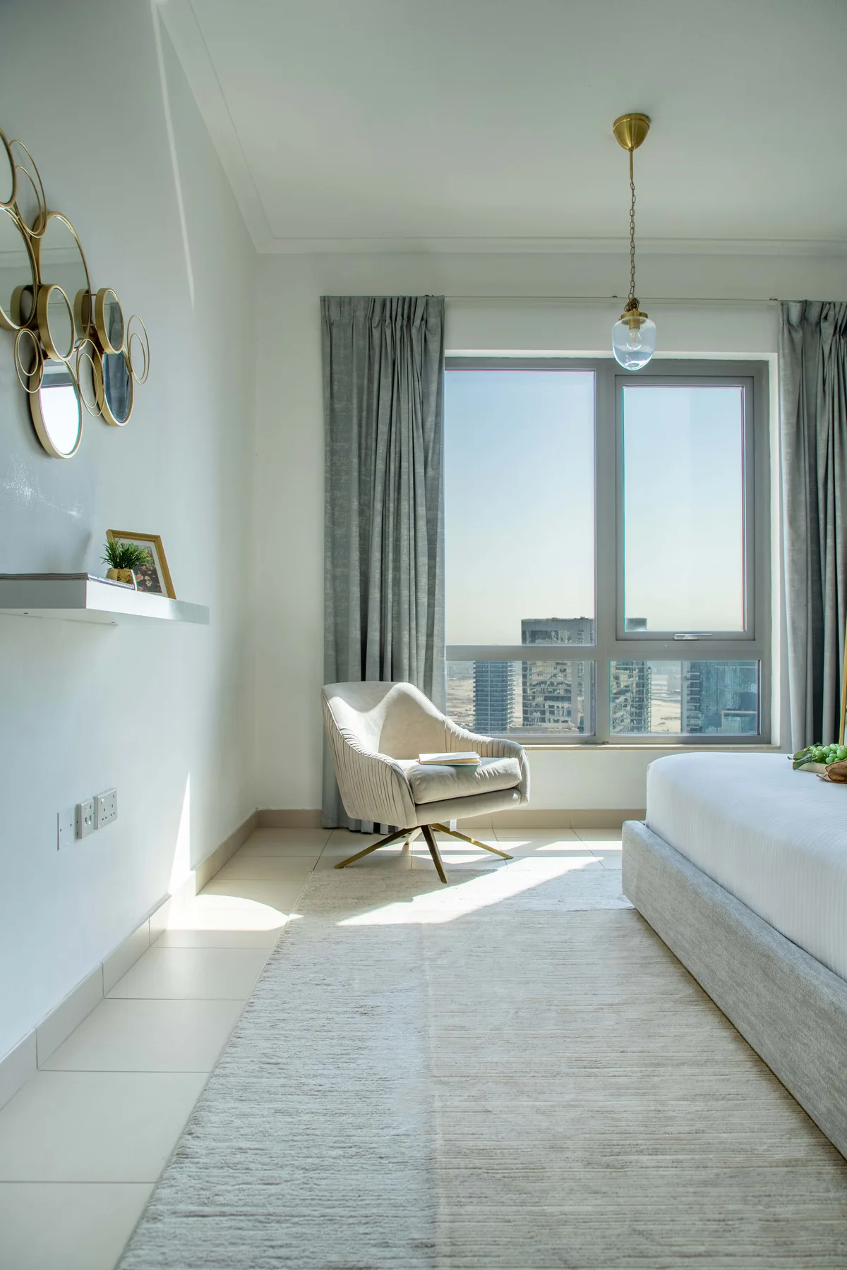 Un dormitorio luminoso con una cama, un sillón y una ventana grande.