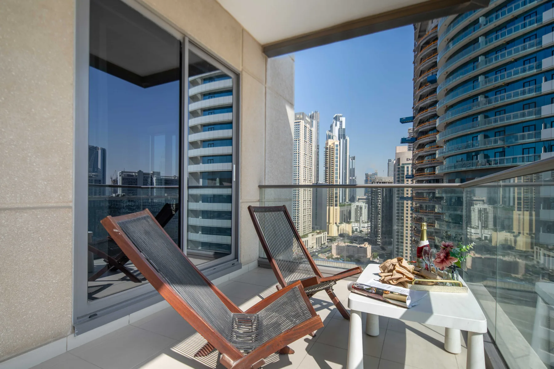 Un balcón con asientos y una mesa, con edificios altos a la vista.