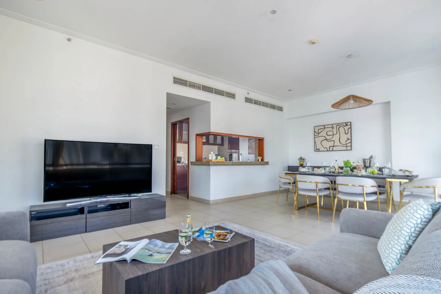 Una sala de estar y comedor con televisión, asientos y una mesa puesta.