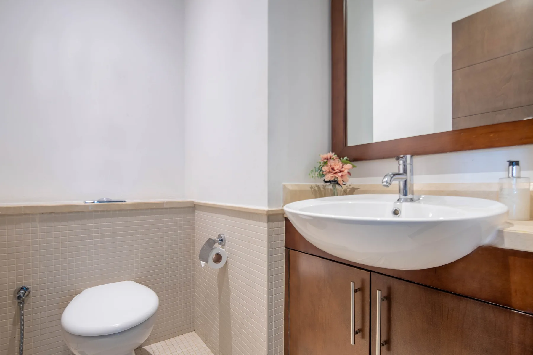 Un baño con lavabo, inodoro y espejo de pared.