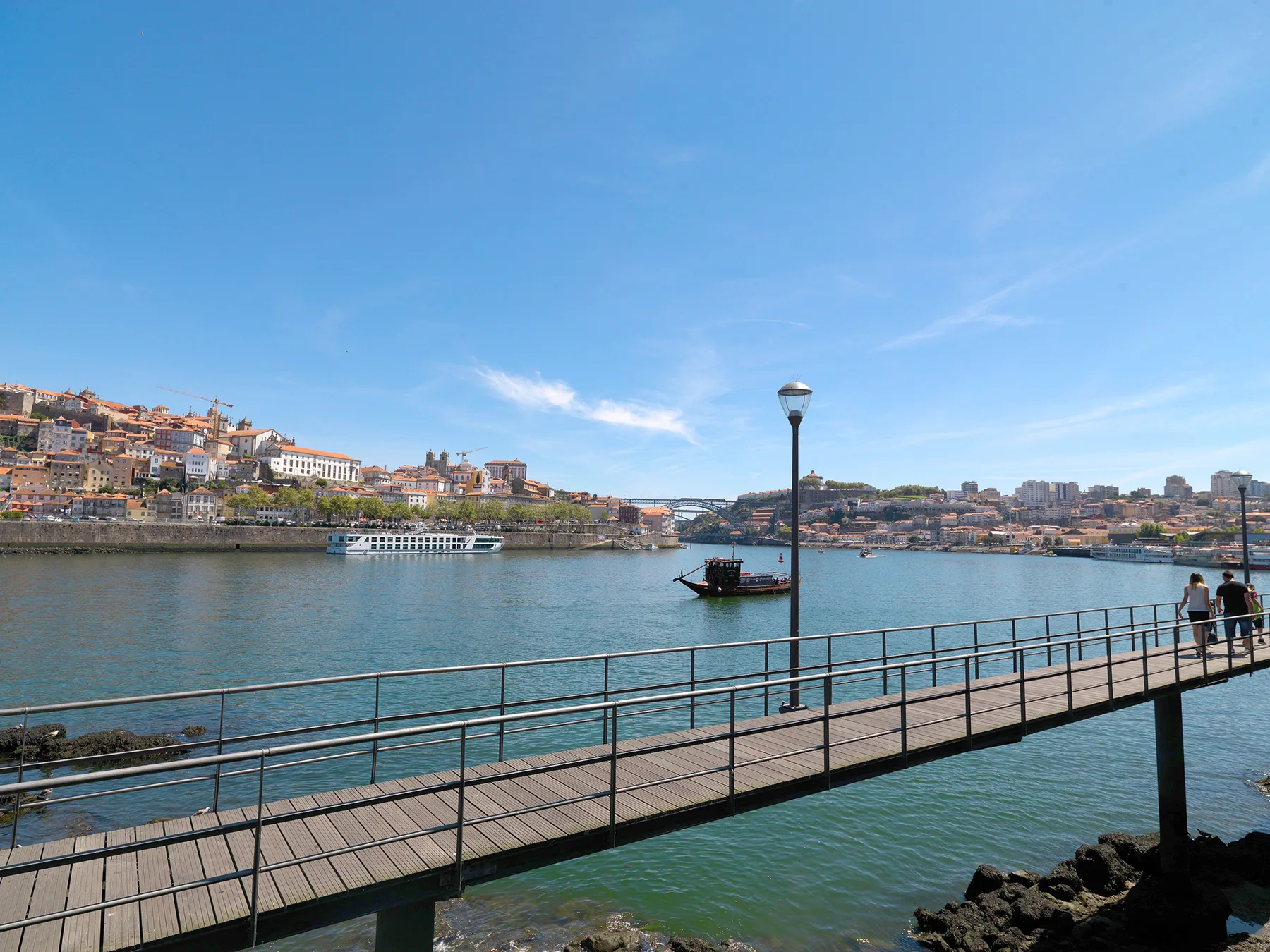 A pedestrian walkway crosses the river, with waterfront buildings visible along the opposite bank.