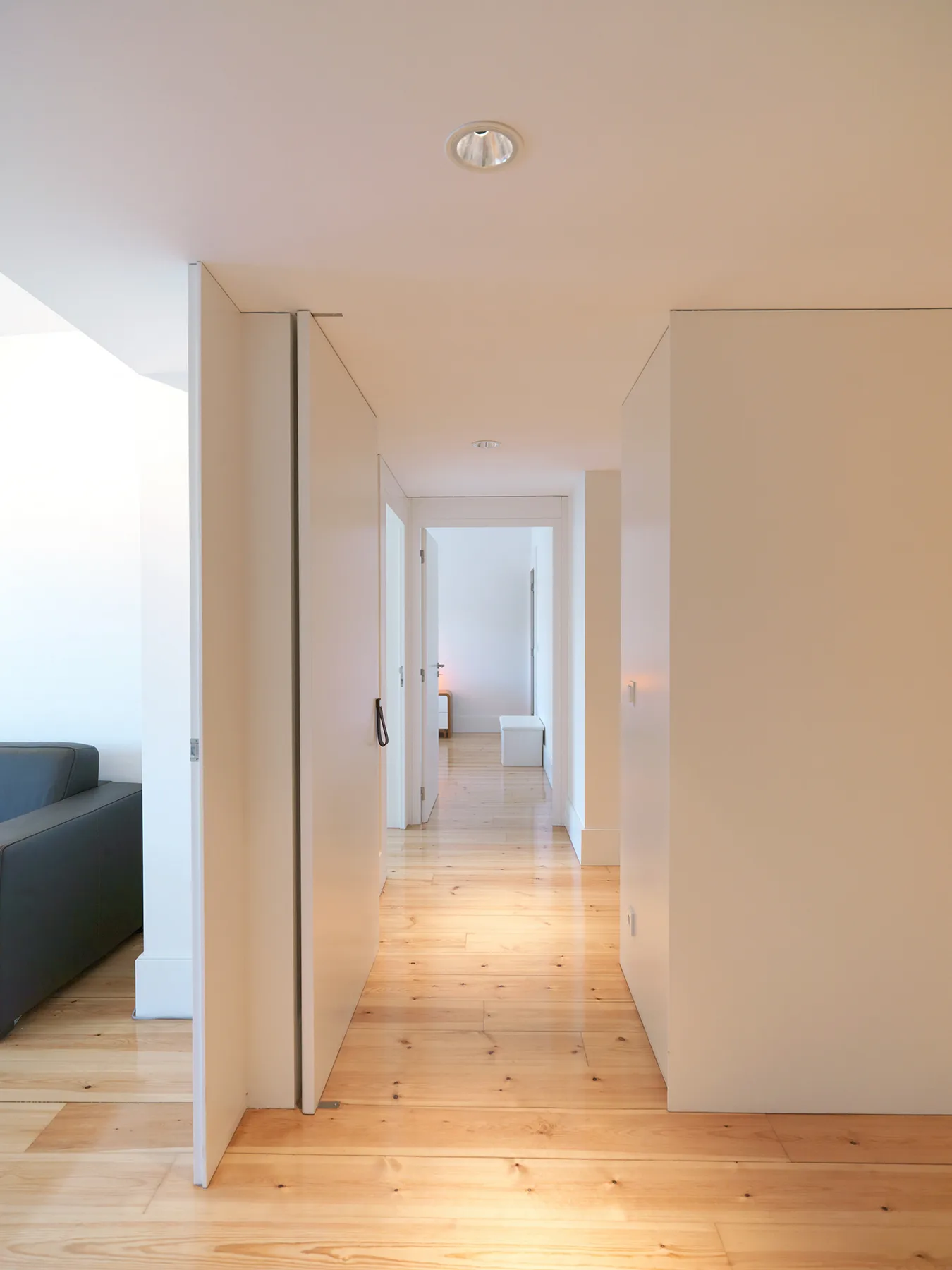 A bright apartment hallway with light wood flooring and open doorways.
