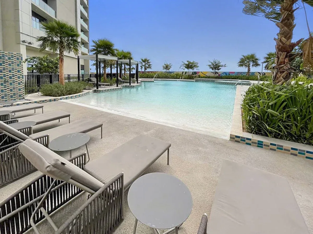 An outdoor swimming pool beside a paved deck with lounge seating.