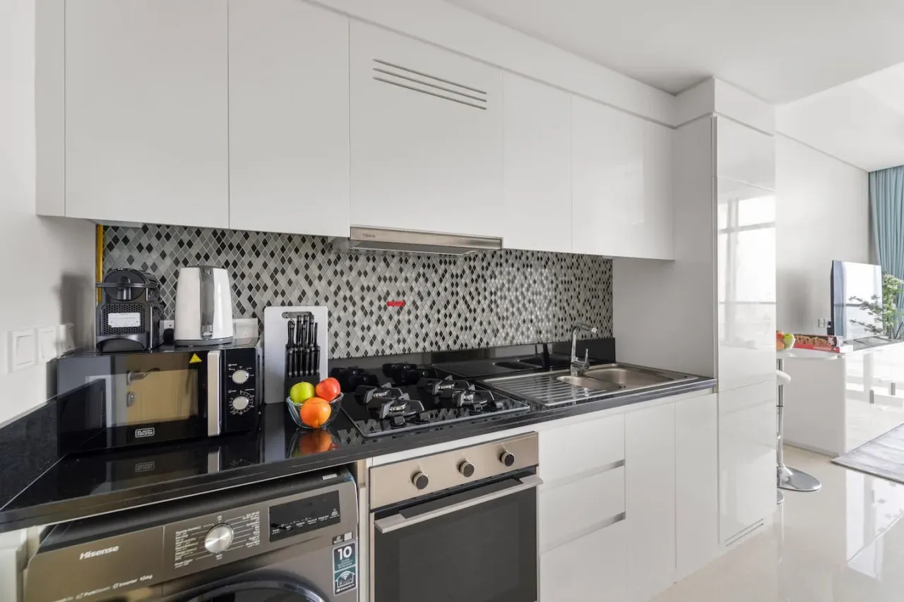 A modern kitchen with a patterned backsplash, countertop appliances, and a built-in cooktop.