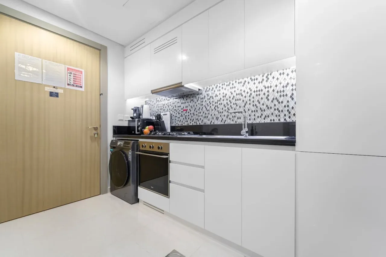 A bright kitchen with white cabinets, a countertop, and a washing machine.