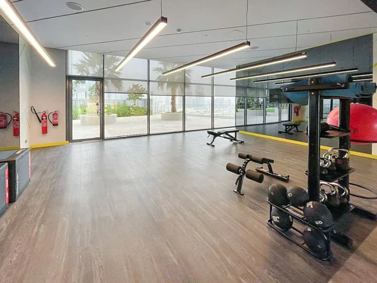 A modern gym with exercise equipment and floor-to-ceiling windows.