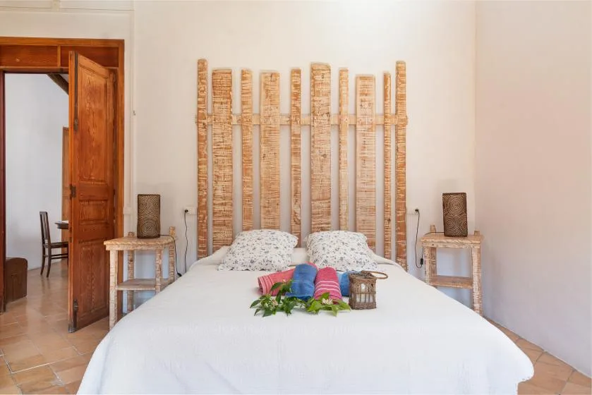 A bedroom with a bed beneath a decorative wooden headboard.