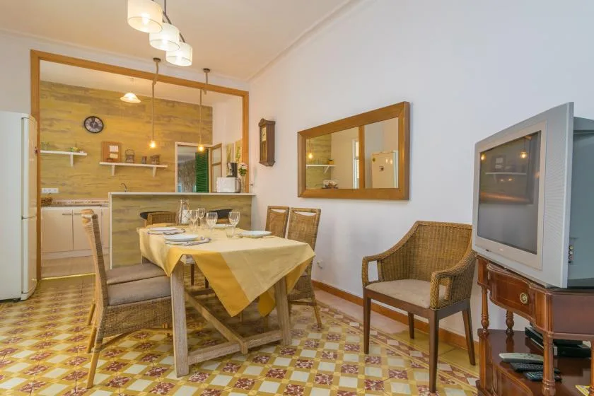A dining area with a set table beside a kitchen and a television.