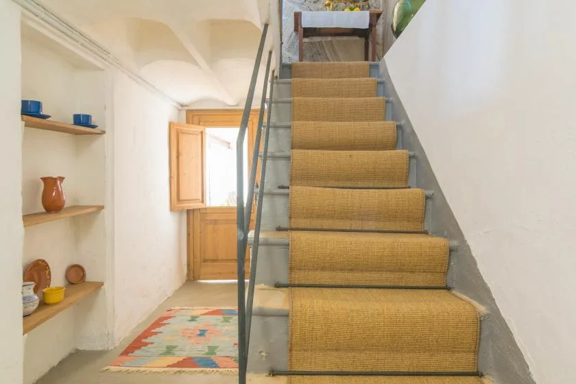 A staircase with tan carpeted steps rises beside a narrow shelving alcove.